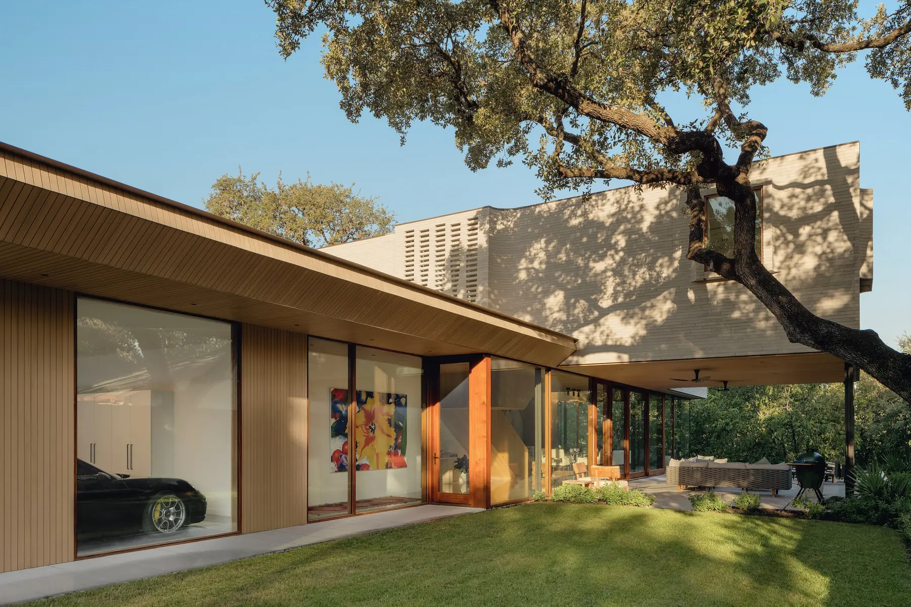 Greenbelt Residence by Risinger Build, with wood cladding under a live oak